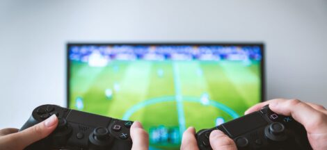 two people holding black gaming consoles