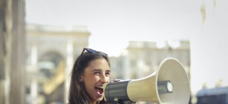 cheerful young woman screaming into megaphone