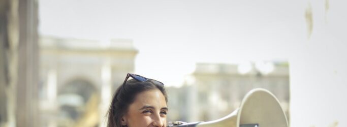 cheerful young woman screaming into megaphone